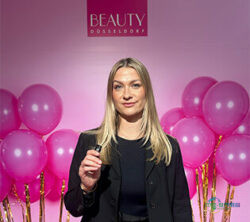 金发女性置身粉色气球与BEAUTY展会标志前；版权：Merken⪼hoenberg