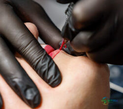 图片：美容师正用细针为客户唇部涂抹红色色素，打造持久唇线；版权：杜塞尔多夫展览中心/ctillmann